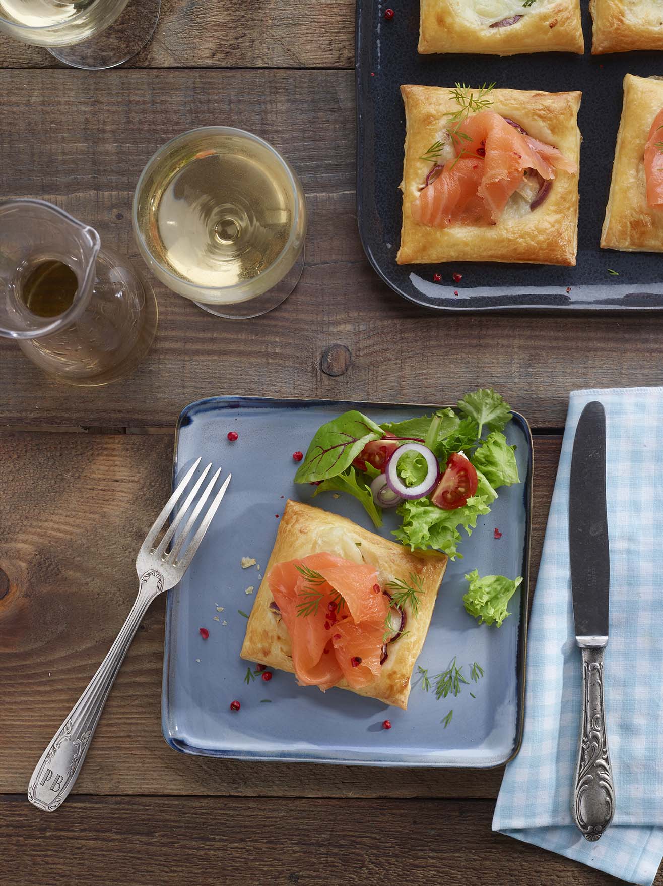 Assiette de feuilleté au saumon fumé, salade et vin blanc.