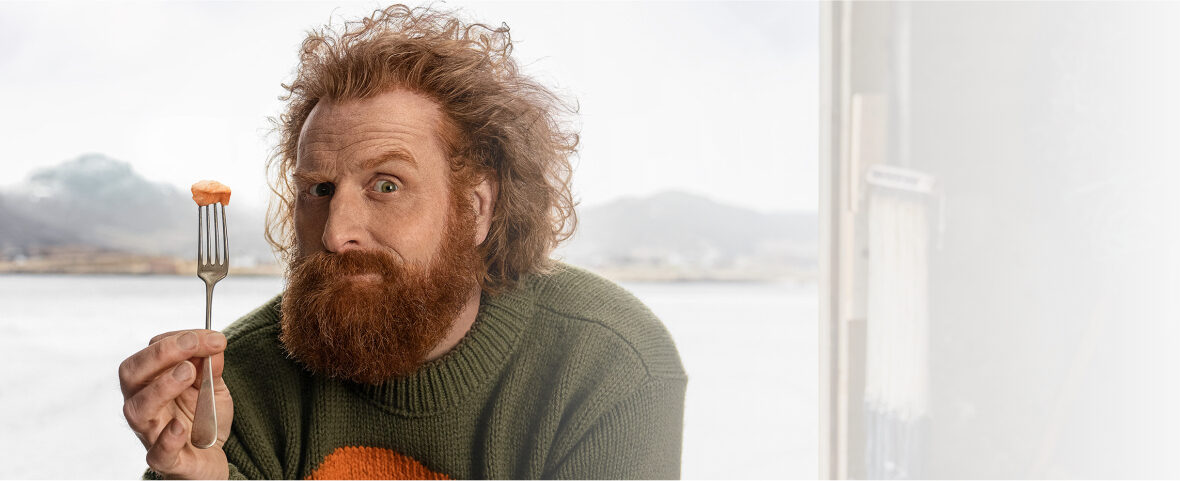 Homme roux perplexe tenant une bouchée sur une fourchette.