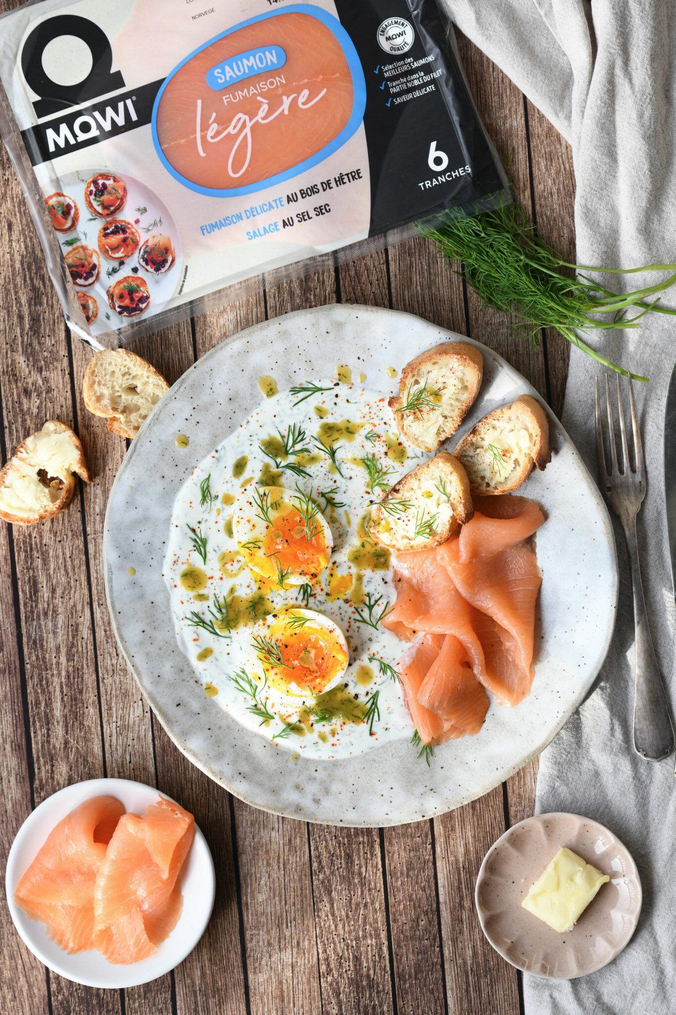 Œufs pochés, saumon fumé et toasts sur un lit de crème à l'aneth et au poivre.
