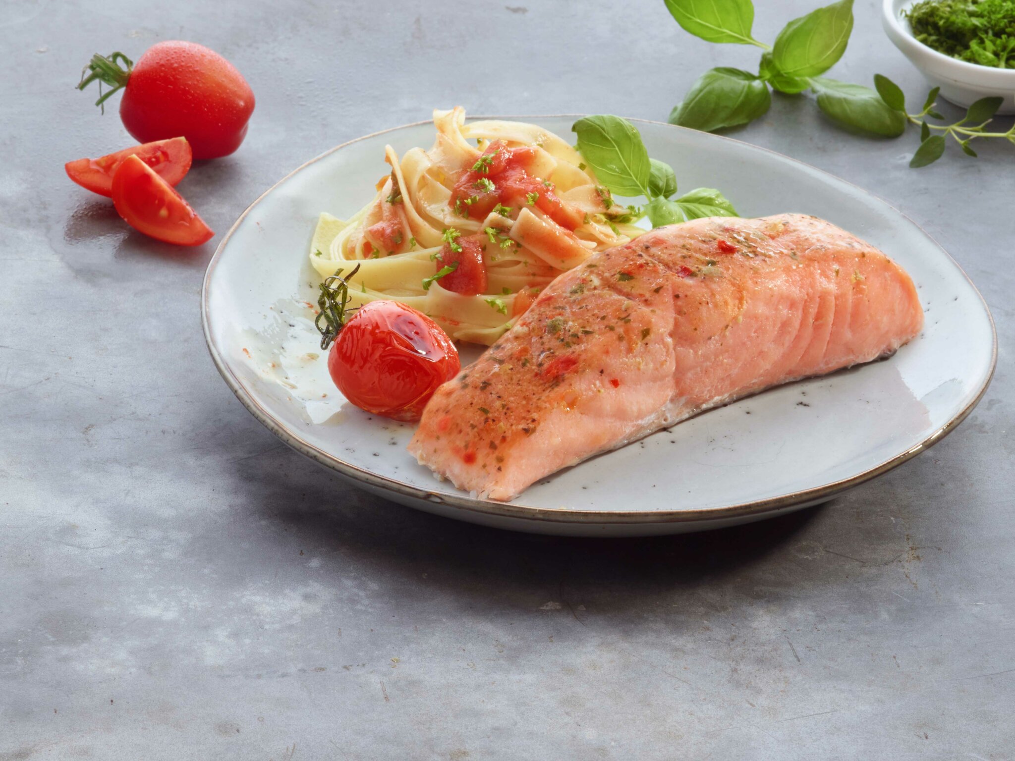 Filet de saumon grillé avec pâtes, tomates cerises et basilic.