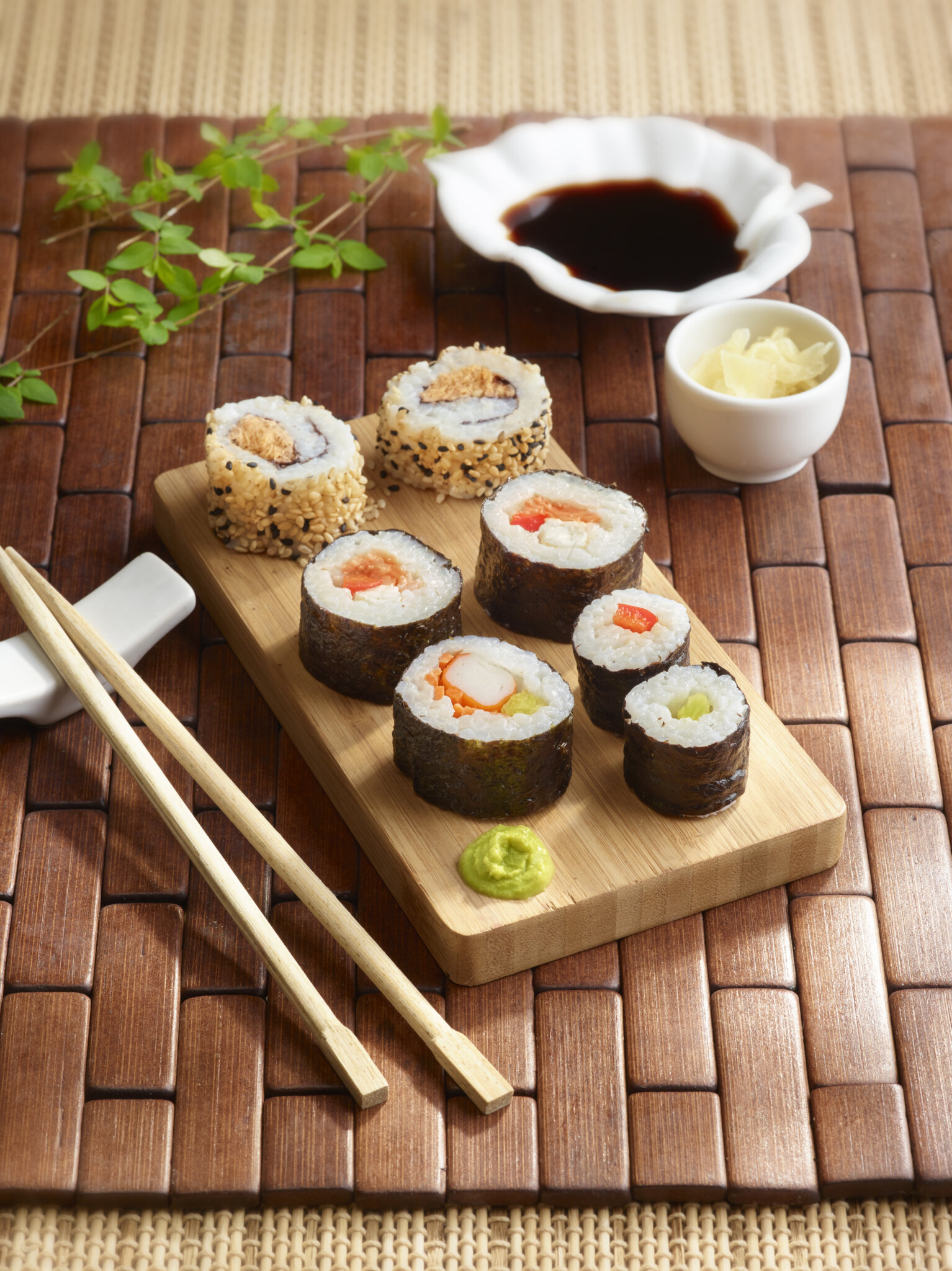 Assortiment de makis et sushis sur planche en bois avec accompagnements.