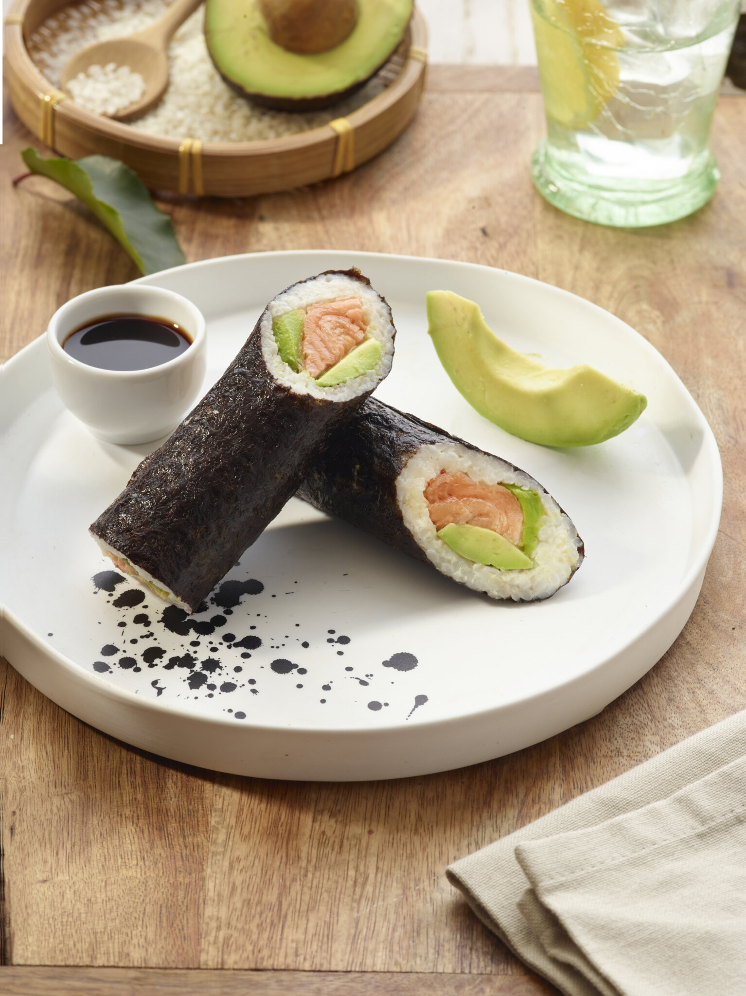 Rouleaux de sushi au saumon et à l'avocat sur une assiette blanche avec sauce soja.