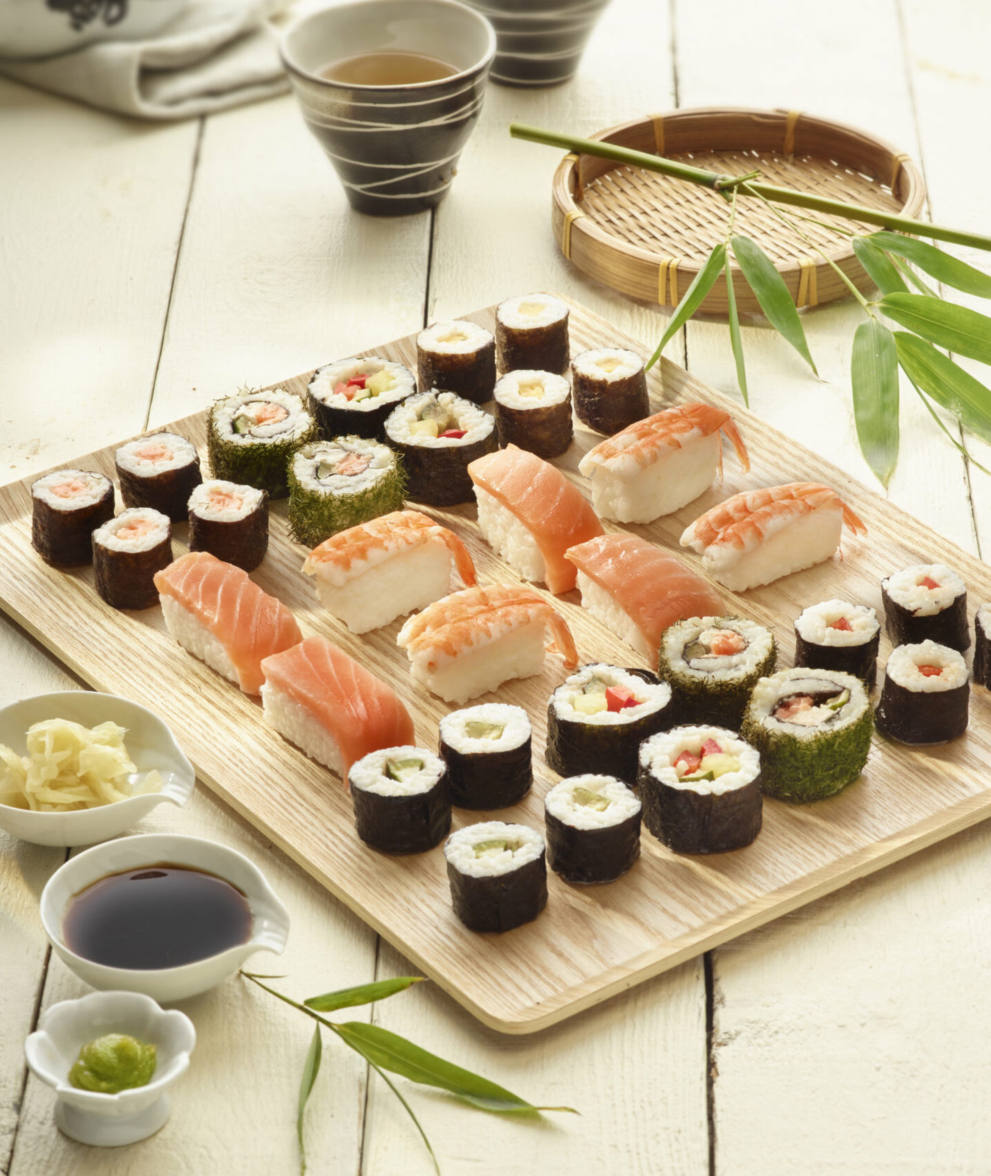 Un plateau de makis et sushis variés avec des accompagnements et du thé.