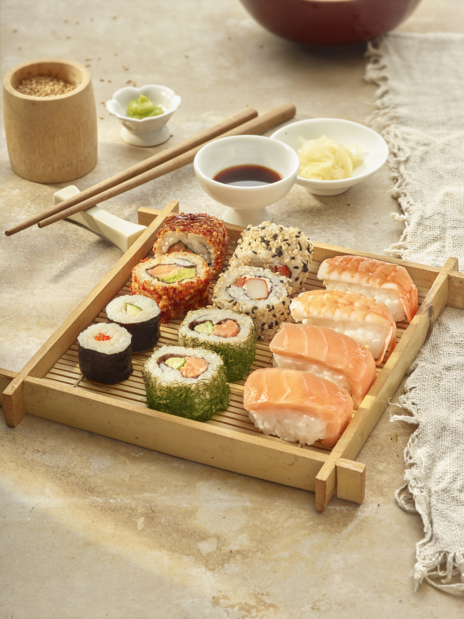 Un plateau de sushis variés avec des makis, nigiris et rouleaux, accompagné de sauce soja et de wasabi.