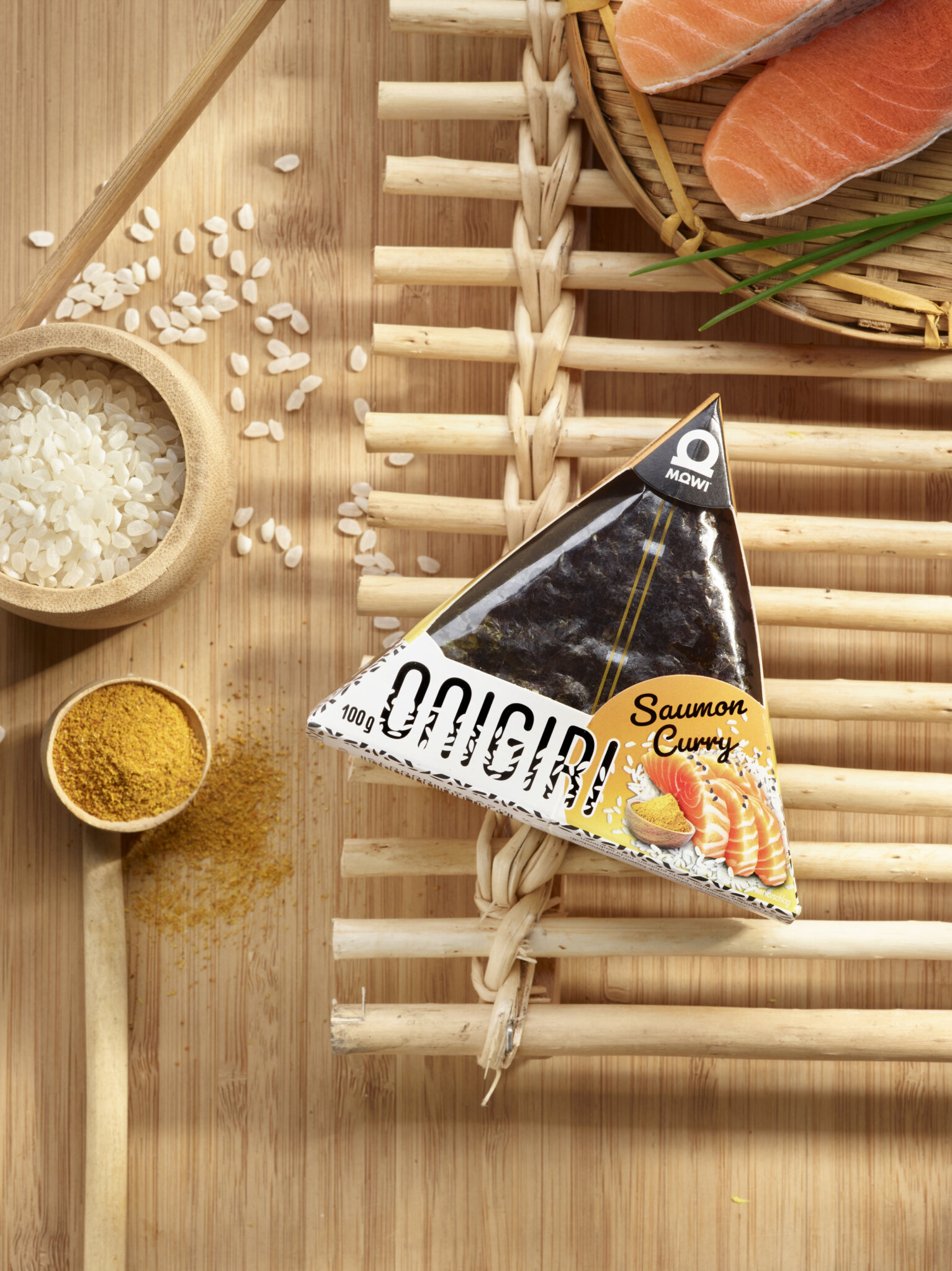 Onigiri Mowi Saumon Curry avec riz, saumon et épices sur fond de bambou.
