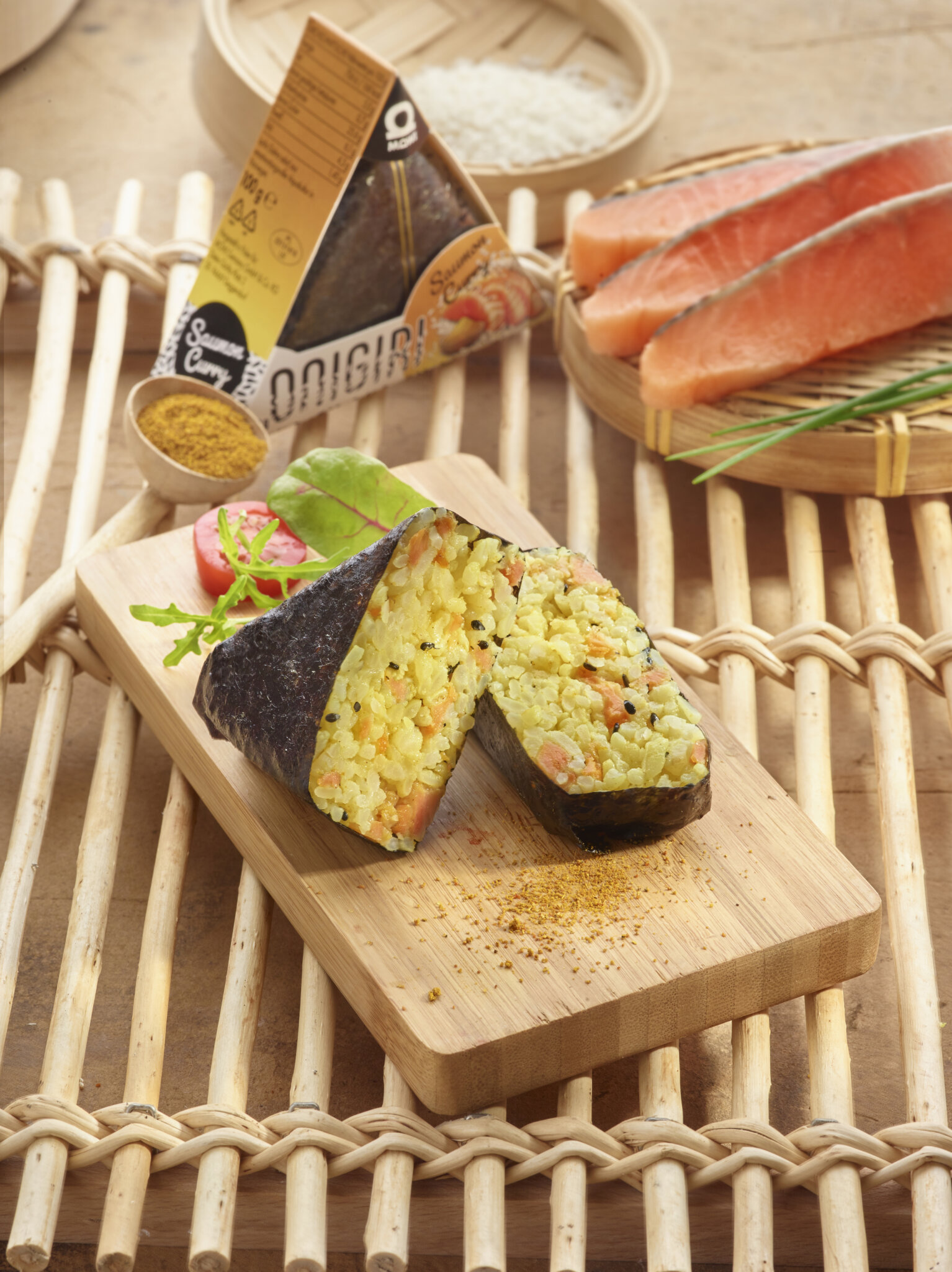 Onigiri au saumon et curry sur planche en bois, entouré d'ingrédients frais.