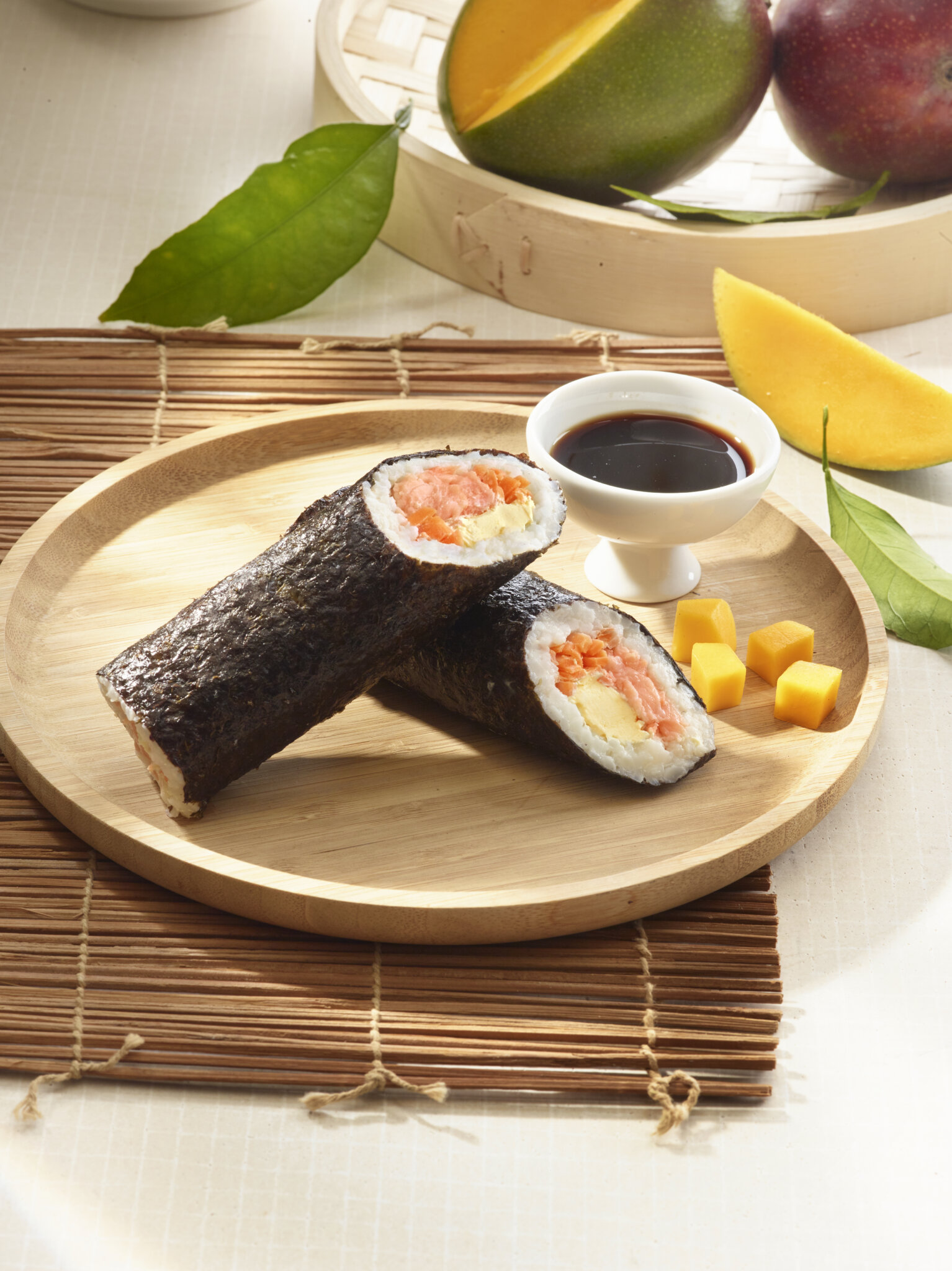 Rouleau de sushi au saumon et mangue, sauce soja, sur plateau en bois.